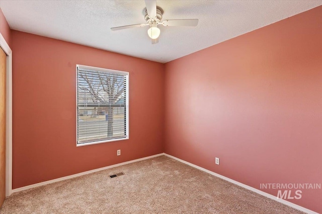 carpeted spare room featuring ceiling fan and a textured ceiling