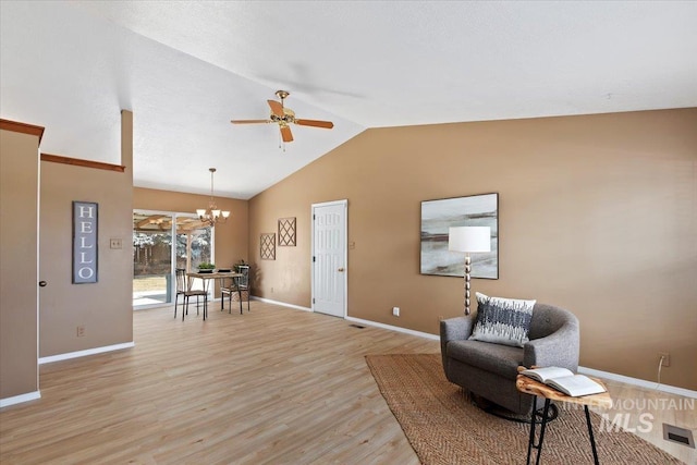 sitting room with lofted ceiling, ceiling fan with notable chandelier, and light hardwood / wood-style flooring