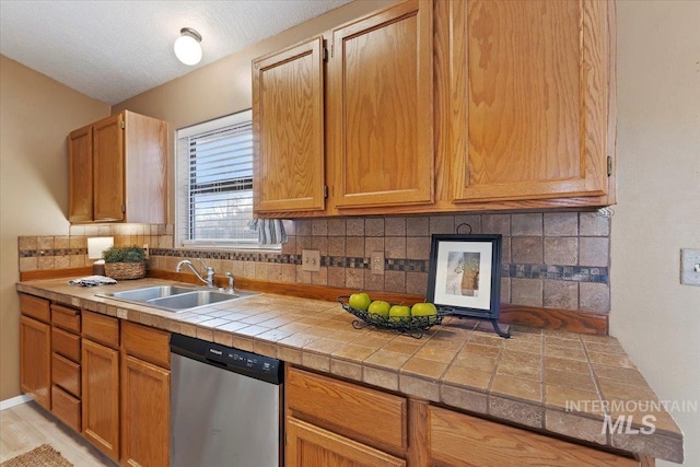 kitchen featuring tasteful backsplash, sink, stainless steel dishwasher, and a textured ceiling