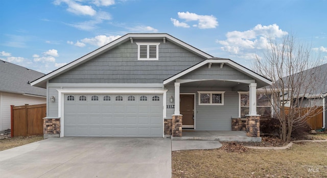 craftsman house with a porch, an attached garage, fence, stone siding, and driveway