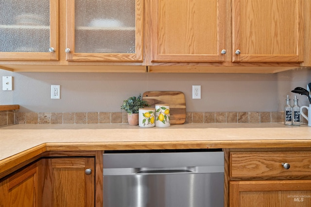 kitchen featuring dishwasher, light countertops, and glass insert cabinets