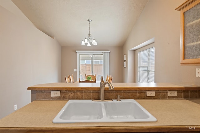 kitchen with glass insert cabinets, decorative light fixtures, vaulted ceiling, a chandelier, and a sink