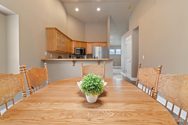 dining space with recessed lighting, a towering ceiling, and baseboards