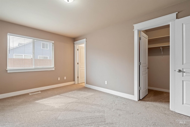 unfurnished bedroom with carpet, visible vents, a spacious closet, and baseboards