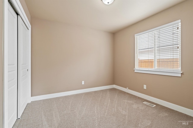 unfurnished bedroom with carpet floors, baseboards, visible vents, and a closet