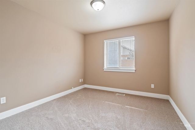 unfurnished room with carpet, visible vents, and baseboards