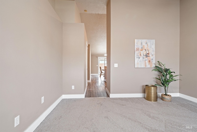 unfurnished room with a textured ceiling, baseboards, and carpet flooring