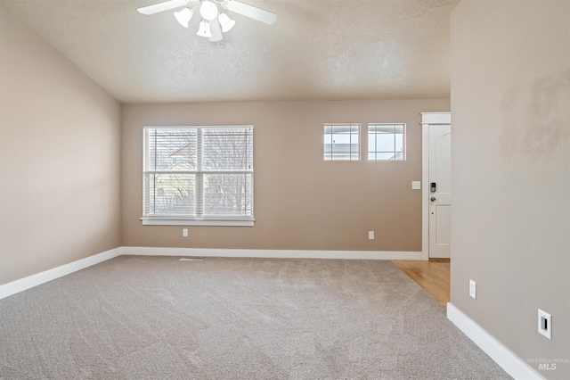 empty room with carpet floors, a textured ceiling, baseboards, and a ceiling fan