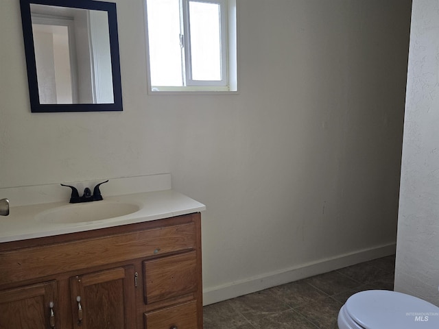 half bath featuring tile patterned flooring, baseboards, vanity, and toilet