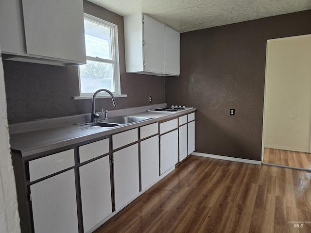 kitchen featuring dark wood-style floors, white cabinets, a sink, and a textured ceiling