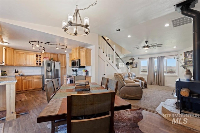 15916 Hill Top Cir, Wilder, ID 83676 - dining space with a wood stove, stairway, a chandelier, wood finished floors, and recessed lighting