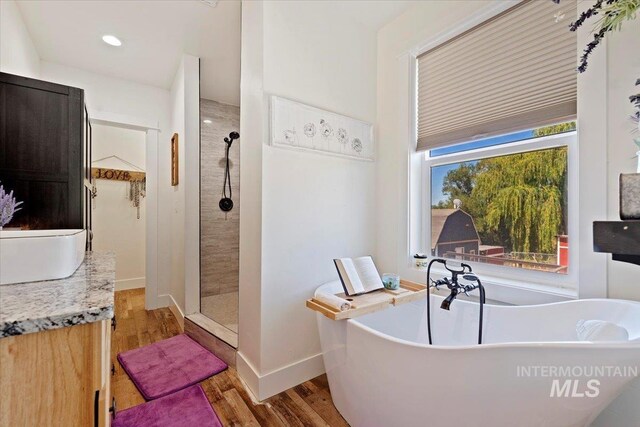 15916 Hill Top Cir, Wilder, ID 83676 - bathroom with a walk in shower, wood finished floors, a freestanding bath, vanity, and recessed lighting