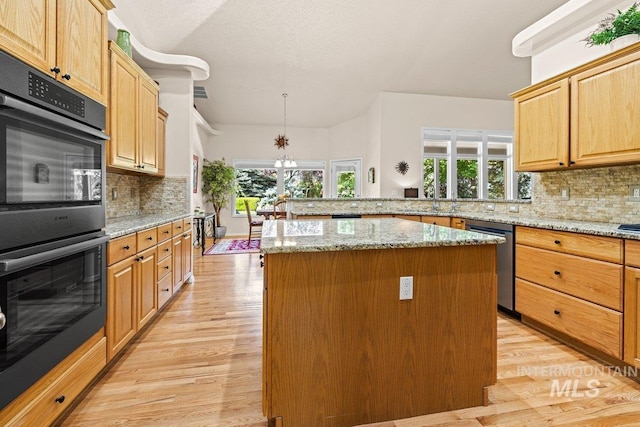 kitchen with dishwasher, multiple ovens, a kitchen island, light wood finished floors, and backsplash