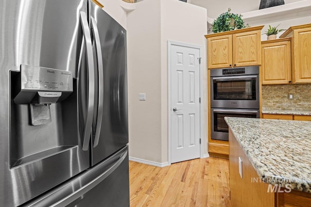 kitchen with appliances with stainless steel finishes, light wood-style floors, tasteful backsplash, baseboards, and light stone countertops