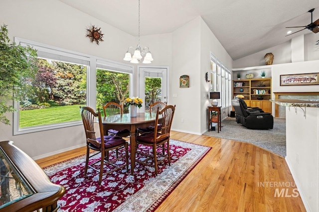 dining room with a chandelier, plenty of natural light, wood finished floors, high vaulted ceiling, and a ceiling fan