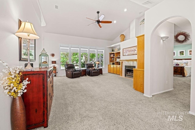 carpeted living area with a ceiling fan, a fireplace, high vaulted ceiling, and baseboards