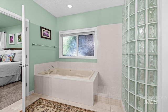 ensuite bathroom featuring a garden tub, tile patterned flooring, a walk in shower, and baseboards