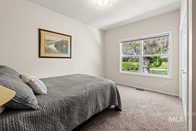 carpeted bedroom featuring baseboards and a textured ceiling
