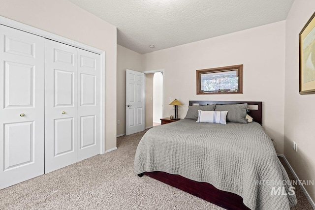bedroom with carpet flooring, a closet, baseboards, and a textured ceiling