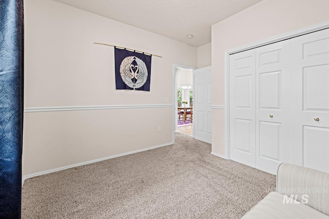unfurnished bedroom with carpet floors, a closet, baseboards, and a textured ceiling