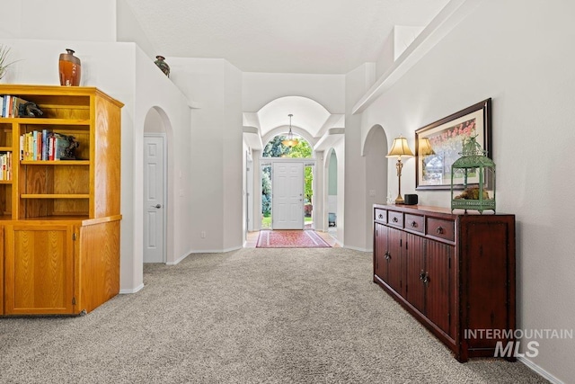 carpeted entryway featuring arched walkways and baseboards