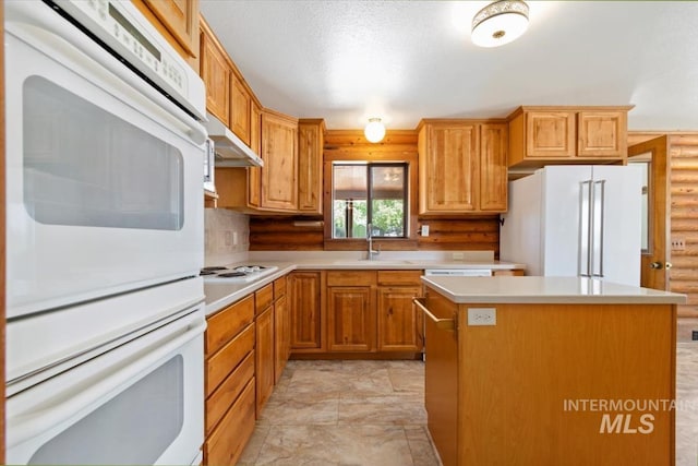 2974 Ua Ave, Emmett, ID 83617 - kitchen featuring white appliances, under cabinet range hood, light countertops, a kitchen island, and log walls