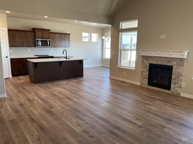 kitchen with lofted ceiling, a sink, open floor plan, decorative backsplash, and stainless steel microwave