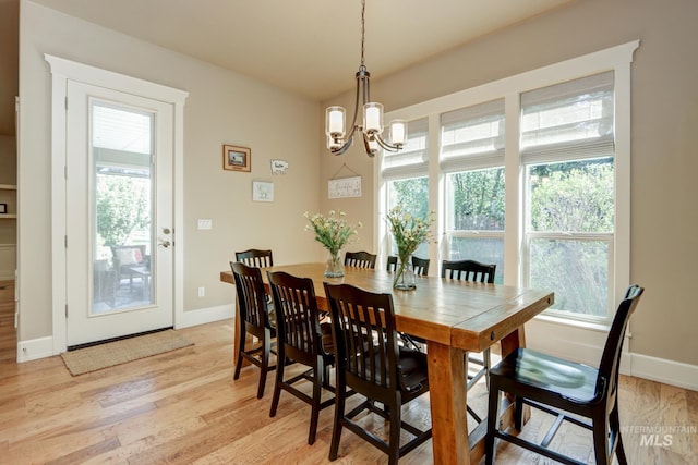 dining space with light wood-style flooring, baseboards, and a notable chandelier