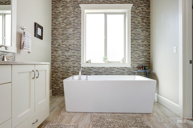 bathroom with a freestanding bath, marble finish floor, and vanity