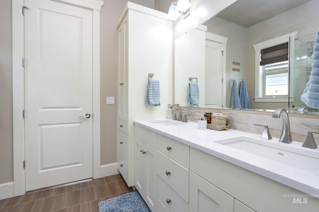 bathroom with baseboards, a sink, and double vanity