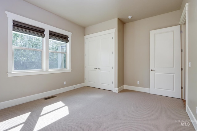 unfurnished bedroom featuring a closet, visible vents, baseboards, and light carpet