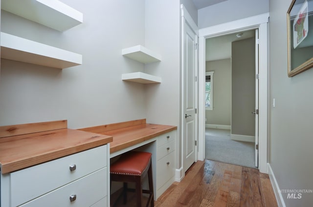 office space with light wood finished floors, baseboards, and built in desk