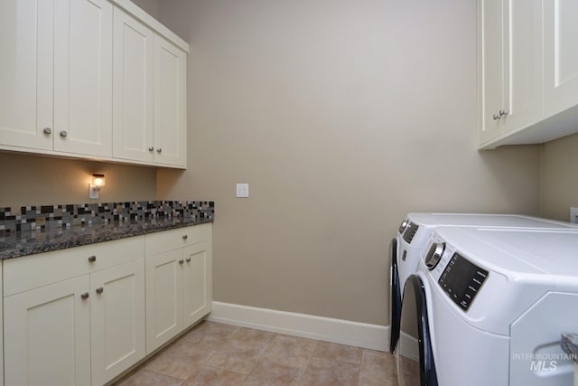 clothes washing area featuring washing machine and clothes dryer, cabinet space, and baseboards