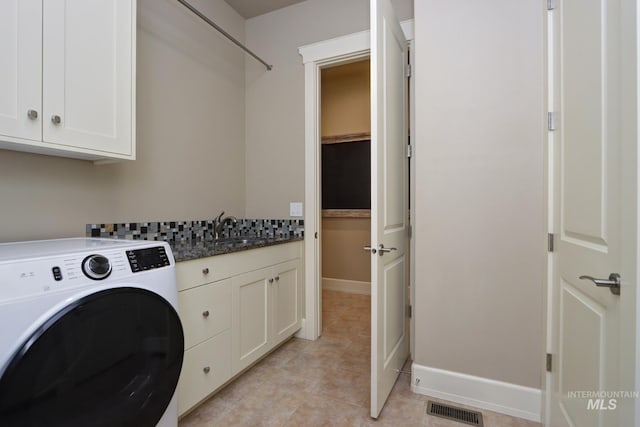 washroom with a sink, visible vents, cabinet space, light tile patterned floors, and washer / dryer