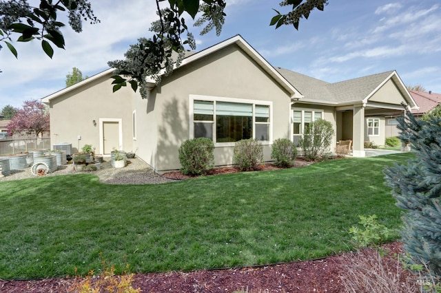 back of house with stucco siding, a yard, and central AC