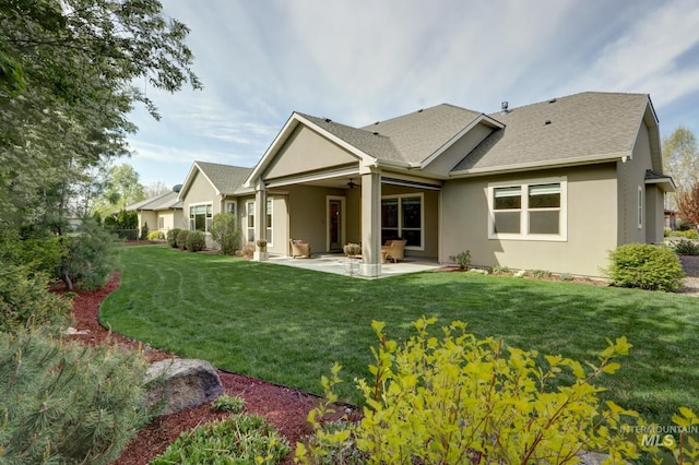 rear view of house with a patio area, a ceiling fan, a shingled roof, a yard, and stucco siding
