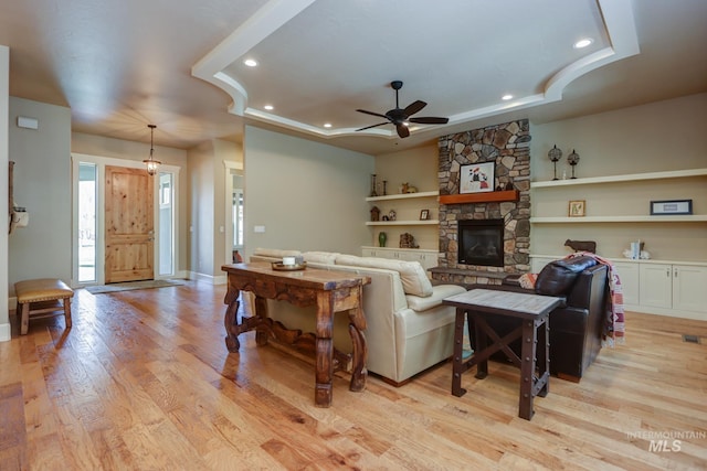 living area with recessed lighting, a stone fireplace, light wood-type flooring, baseboards, and ceiling fan