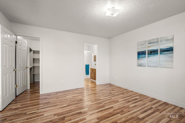 81 N Mirage St, Nampa, ID 83651 - unfurnished bedroom with baseboards, a spacious closet, light wood-type flooring, a textured ceiling, and ensuite bath