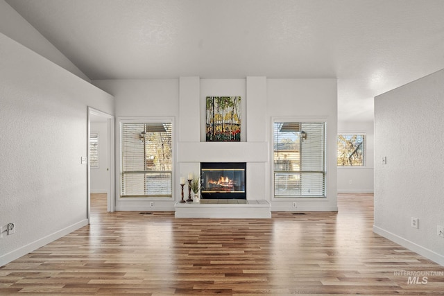81 N Mirage St, Nampa, ID 83651 - unfurnished living room featuring wood finished floors, a textured wall, baseboards, and a glass covered fireplace