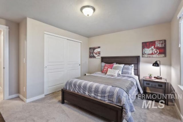 carpeted bedroom featuring baseboards and a closet