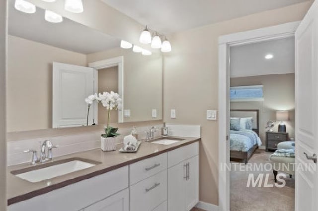 full bath featuring double vanity, connected bathroom, and a sink