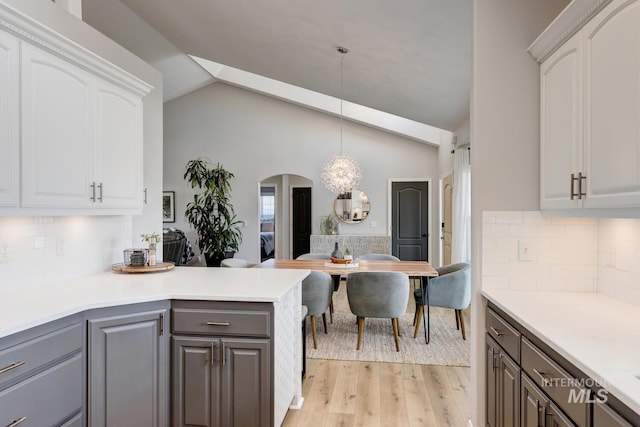 10551 W Deep Canyon Dr, Star, ID 83669 - kitchen with light wood-style floors, arched walkways, vaulted ceiling, white cabinetry, and gray cabinets