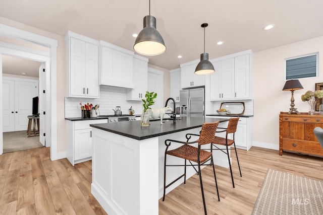 10179 Silversun St, Nampa, ID 83687 - kitchen with stainless steel fridge, a sink, light wood-style flooring, dark countertops, and recessed lighting