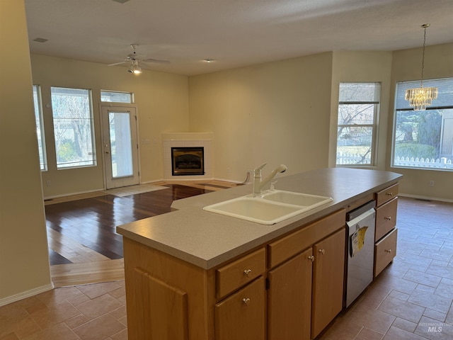 kitchen featuring dishwasher, a center island with sink, hanging light fixtures, sink, and ceiling fan with notable chandelier