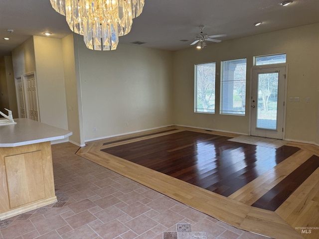 unfurnished dining area with ceiling fan with notable chandelier