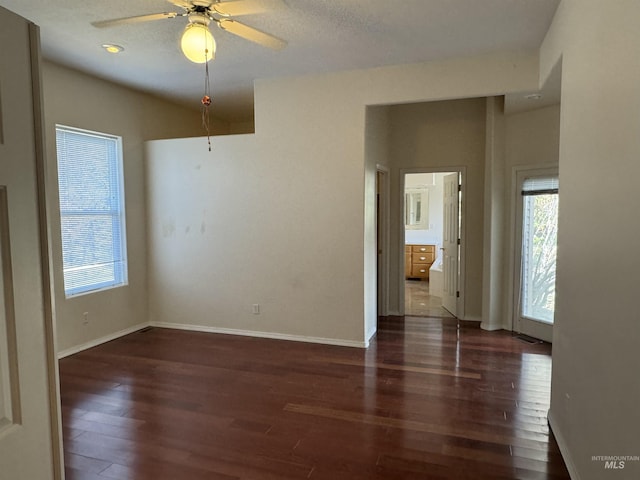 empty room with ceiling fan, dark wood-type flooring, and a textured ceiling