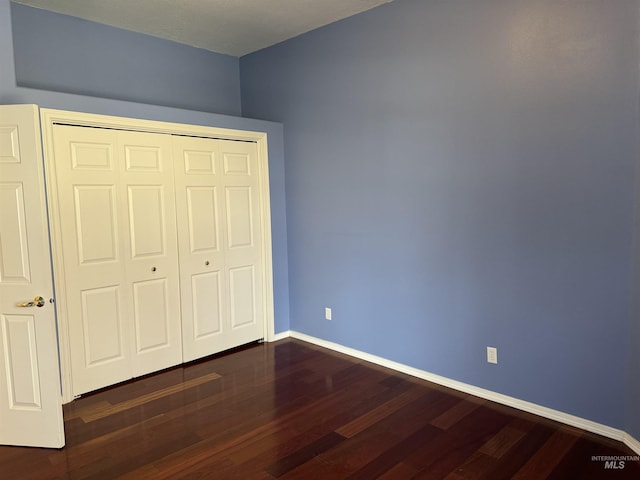 unfurnished bedroom with a closet and dark hardwood / wood-style floors