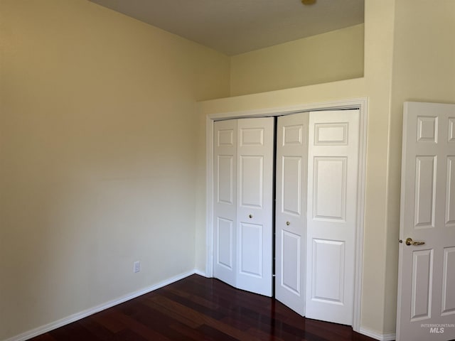 unfurnished bedroom with a closet and dark hardwood / wood-style floors