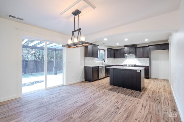 12476 W Kempshire Ct, Star, ID 83669 - kitchen with appliances with stainless steel finishes, light wood-type flooring, decorative backsplash, light countertops, and a center island