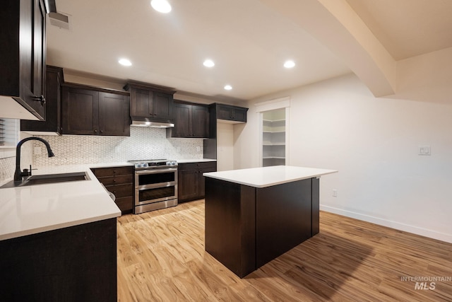 12476 W Kempshire Ct, Star, ID 83669 - kitchen featuring double oven range, under cabinet range hood, light wood-style floors, tasteful backsplash, and recessed lighting